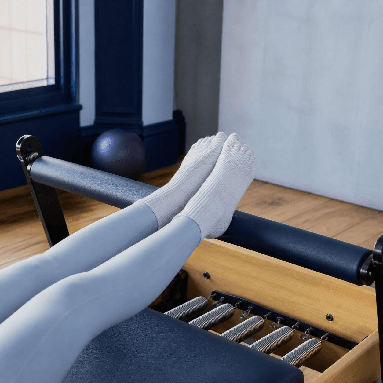 Socks pressing against a reformer footbar above the carriage springs