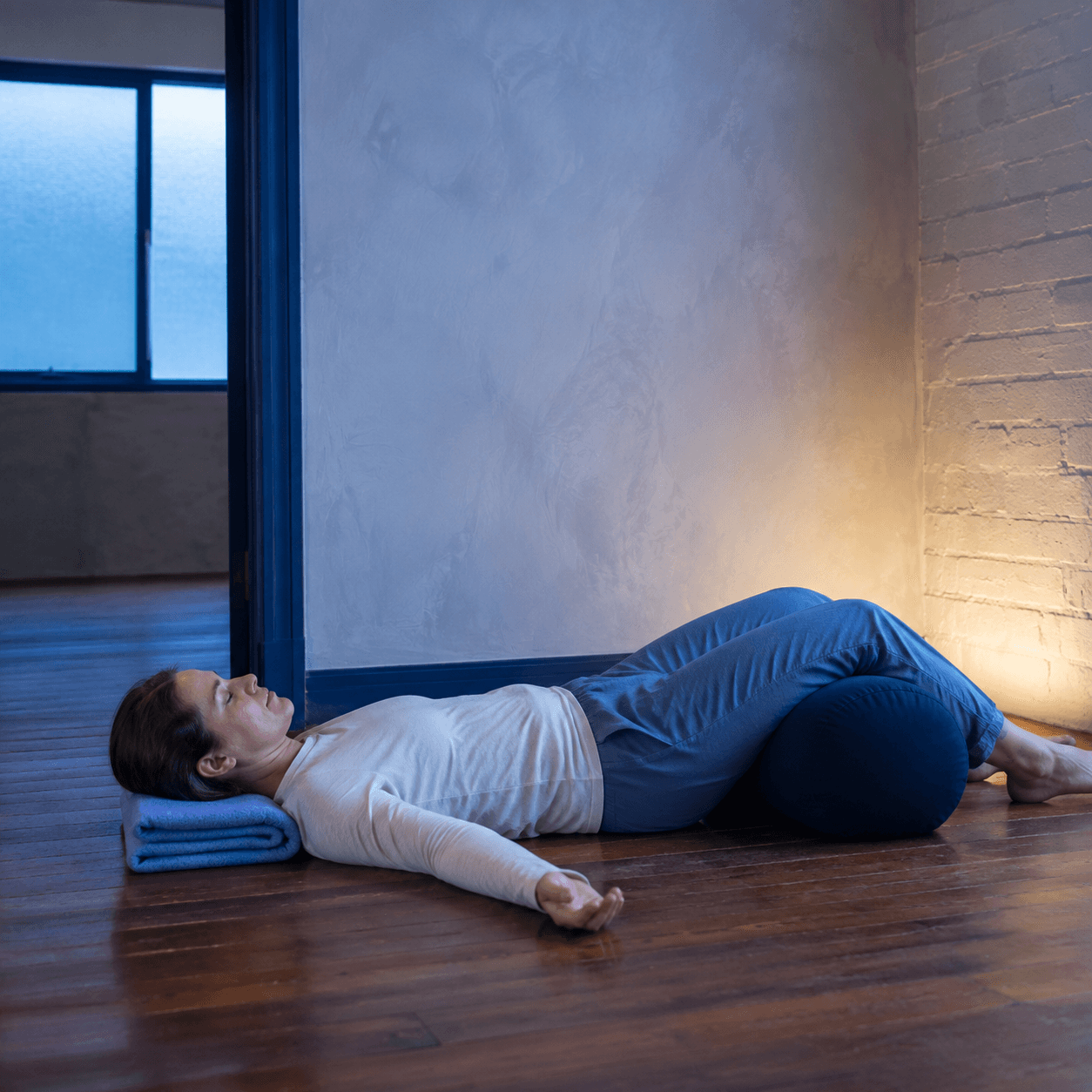 Student resting in a supported restorative pose in soft blue-hour light