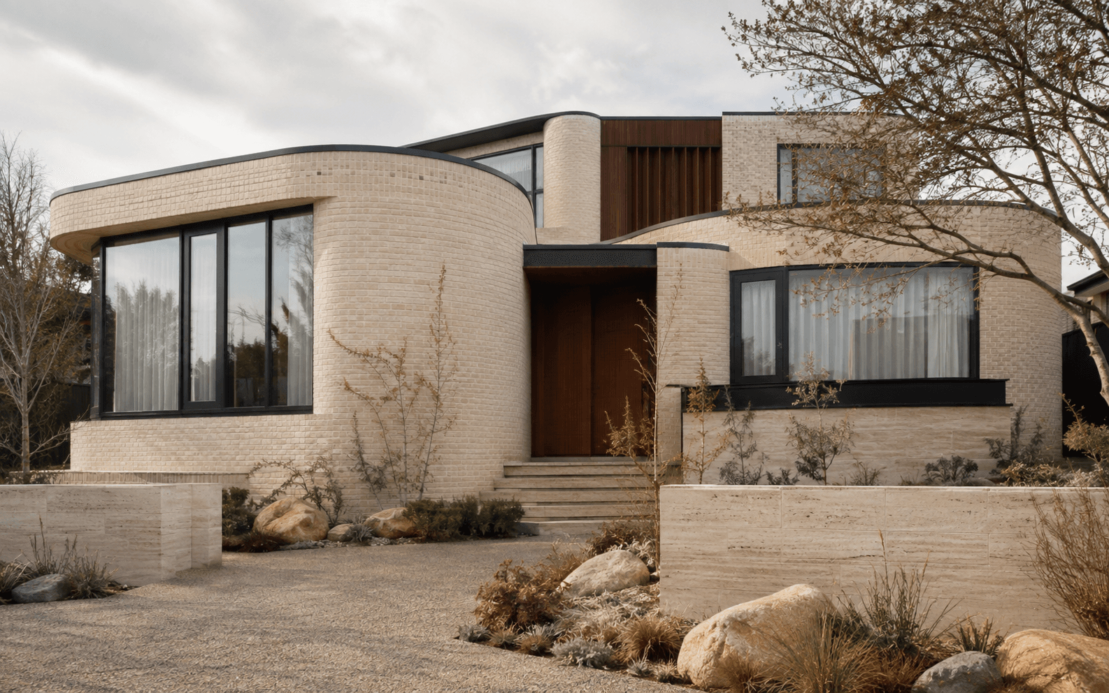Curved cream-brick contemporary family home with a dark timber entry in Armadale