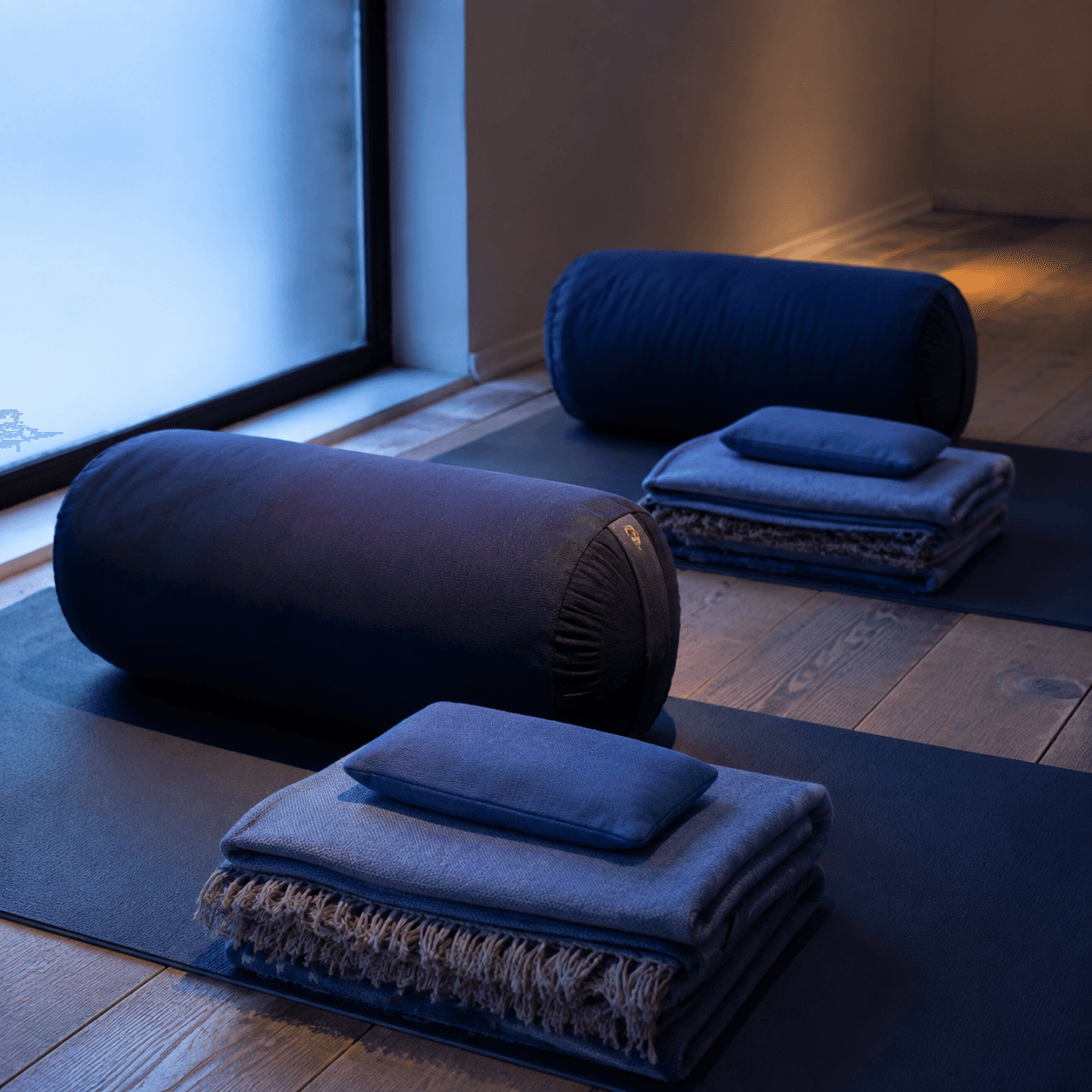 Bolsters and folded blankets arranged for a restorative class in low light